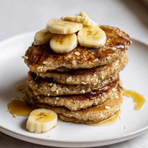 Delicious stack of fluffy banana oat pancakes, perfect for a weekend breakfast treat with berries.