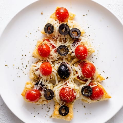 Warm, cheesy Puff Pastry Christmas Tree Pizza Bites with basil, ideal for a holiday appetizer tray.