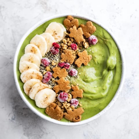 A vibrant Gingerbread Cookie Matcha Breakfast Smoothie Bowl, topped with fresh fruit and gingerbread cookie crumbles for a festive start.