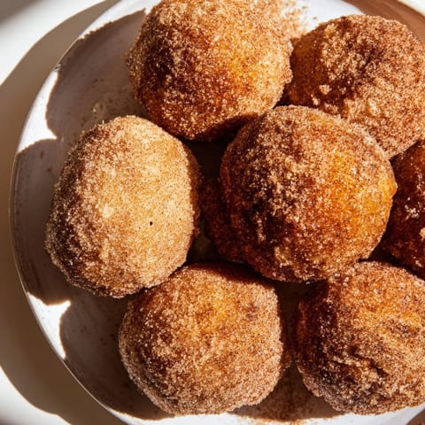 Close-up of fluffy air fryer cinnamon donuts, invitingly dusted with cinnamon sugar, perfect for a treat.