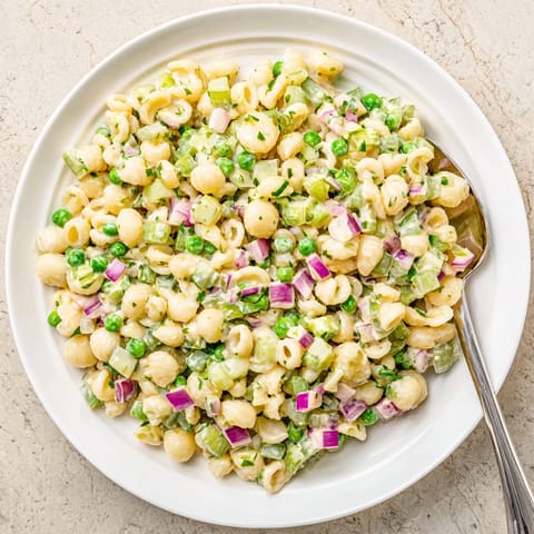 A chilled bowl of Creamy Dill Pickle Pasta Salad garnished with fresh dill, ready for a sunny picnic spread.  
