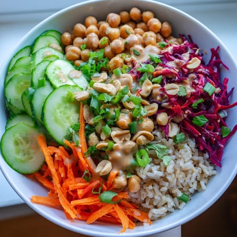 This easy Peanut Chickpea Rice Bowl features golden roasted peanuts, crisp cucumber, and shredded carrots tossed in a zesty ginger peanut sauce.  