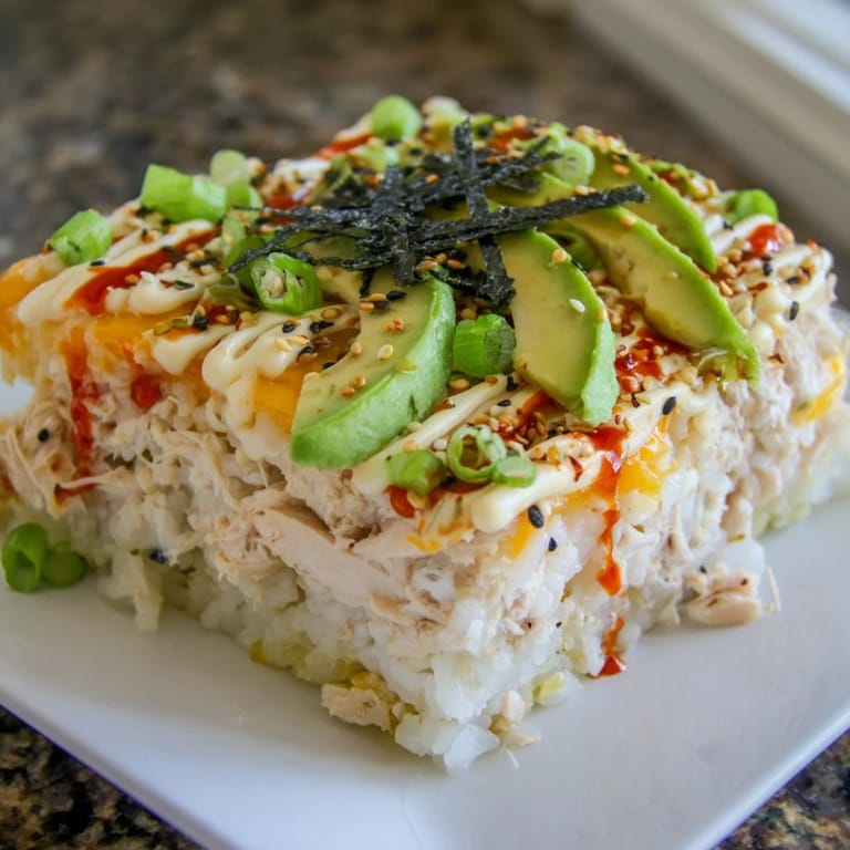 A close-up of a creamy Chicken Sushi Bake, layered with seasoned rice and sesame seeds topping.